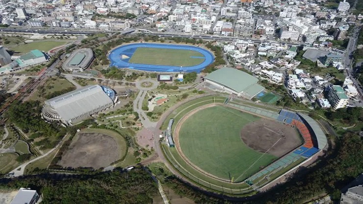 2024年、東京ヤクルトスワローズがキャンプを行うANA BALL PARK 浦添。青空の下、緑鮮やかな天然芝グラウンドで練習する選手たちの姿が活写されている。
